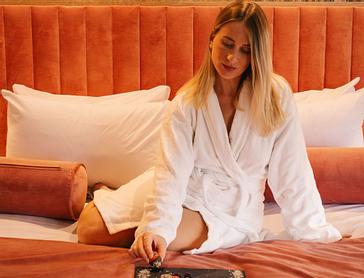 HYDE Hotel | Galway | A woman in a white bathrobe sitting on a stylish bed